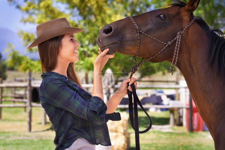 Foto de Vaquera, sonrisa y mujer con caballo en la granja al aire libre en verano o la naturaleza en Texas para la recreación. Occidental, feliz persona femenina y animal en el rancho, mascota o semental en el campo rural para el cuidado. - Imagen libre de derechos