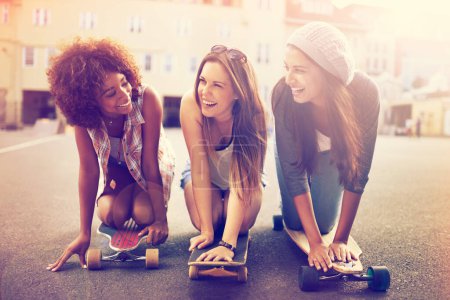 Photo for Skatepark, laugh and friends in street for balance, hobby or competition in city. Skater, lens flare and diverse group of women with skateboard for training, exercise or happiness in outdoor activity. - Royalty Free Image