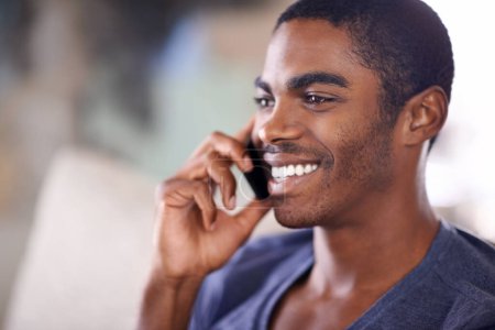 Photo for African man, phone call and home on sofa with smile for conversation, contact and listening in lounge. Person, smartphone and happy for mobile connection, talking and chat on couch in house - Royalty Free Image