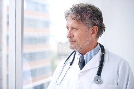 Photo for Doctor, thinking and man at window in office planning future surgery or ideas for medical process in clinic. Medicine, innovation and mature surgeon remember a solution in healthcare and hospital. - Royalty Free Image