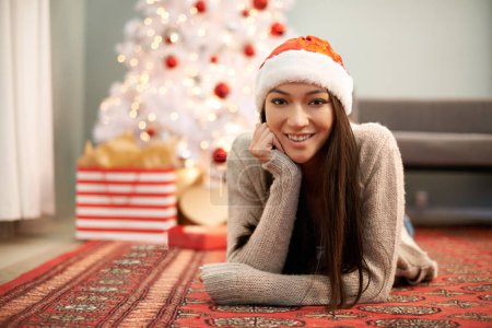 Photo for Portrait, smile and Christmas with young woman in living room of home for festive celebration. Face, gift or present and happy relaxed person with Santa hat in apartment for December holiday season. - Royalty Free Image