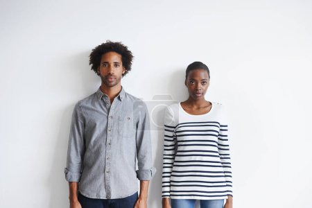 Photo for Couple, serious and portrait by white wall in fashion with confidence, casual style and model aesthetic. Black woman, and face of man with trendy apparel, edgy clothes and pride with calm expression. - Royalty Free Image