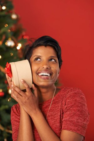 Photo for Christmas, excited and woman guess gift in box at home for holiday celebration on mockup space in India. Happy person, xmas and shaking present or listening to package for festive season in house. - Royalty Free Image