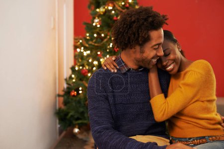 Photo for Couple, embrace and Christmas holiday at tree in apartment living room for festive season celebration, vacation or decoration. Man, woman and hug bonding for relaxing connection, present or break. - Royalty Free Image