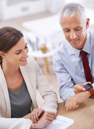 Photo for Business people, colleagues and smart watch in office with future technology, screen or online. Mature, male person and woman with smile at finance agency or time management, teamwork or corporate. - Royalty Free Image
