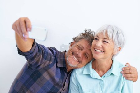 Photo for Old couple, selfie and hug, happy together and social media post for memory and love on white background. Trust, support and loyalty with people in marriage, smile in picture for post and mobile app. - Royalty Free Image