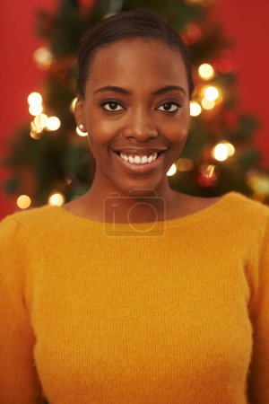 Téléchargez les photos : Noël, arbre et portrait de femme noire à la maison en vacances ou vacances festives avec bonheur. Africaine, fille et sourire à Noël avec énergie excitée et lumières pour briller dans le salon de la maison. - en image libre de droit