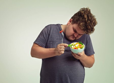 Photo for Bowl, man and thinking with salad in studio for healthy diet, weight loss and examine food. Plus size, male person and contemplating with organic meal for detox, lifestyle change and nutrition. - Royalty Free Image