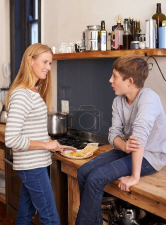 Photo for Mother, child and cooking food in kitchen for morning breakfast on counter for toast meal, brunch or snack. Woman, son and conversation in home for healthy nutrition or hungry, wellness or together. - Royalty Free Image