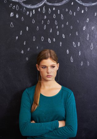 Photo for Rain, sad and woman with cloud on chalkboard for depression, unhappy and upset mood. Storm, winter weather and person with crossed arms for attitude, emotion and worry expression on dark background. - Royalty Free Image