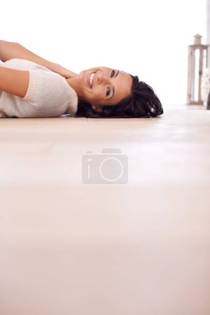Photo for Woman, portrait and smile on floor for relax with mock up space, weekend break and confidence in apartment. Person, lying down and face with happiness in home on wooden flooring for fun and ground. - Royalty Free Image