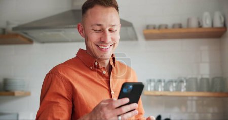 Photo for Man, kitchen and typing on phone or browsing social media at home, happy and relaxing on weekend. Happy male person, communication and mobile application for online conversation, humor and laughing. - Royalty Free Image