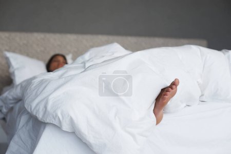 Photo for Lazy, feet and woman in bedroom sleeping, house and white duvet for bedding, nap and exhausted. Morning, dream and female person on day off to relax in apartment, rest and cosy with blanket on bed. - Royalty Free Image