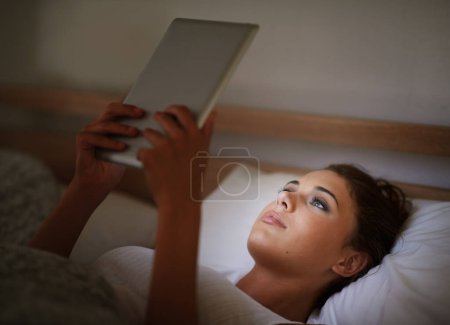 Photo for Woman, tablet and bed at night, social media and entertainment with tech and relaxing for peace before sleep. Female person, browsing and online for home, internet and ebook or scrolling and research. - Royalty Free Image