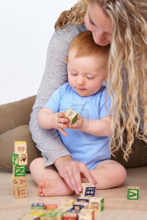 Photo for Mother, baby and playing with wooden blocks or toys for childhood development or bonding at home. Mom, toddler and little boy learning shapes, letters or building together for fun activity at house. - Royalty Free Image