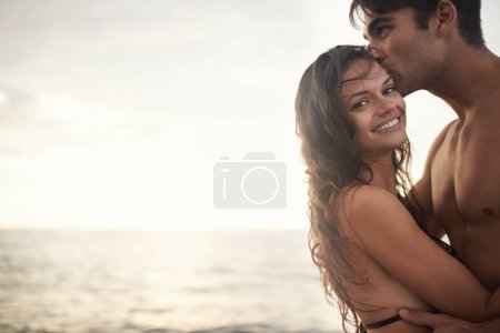 Photo for Portrait, happy couple and kiss at sea at sunset on vacation, holiday or travel together. Face, man and woman at ocean for adventure, romance or connection in summer by water for love on mockup space. - Royalty Free Image