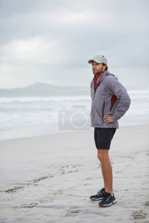 Photo for Fitness, break and man thinking at a beach after training, running or winter morning cardio in nature. Workout, recovery and male runner at the sea for sports rest, breathing or body wellness routine. - Royalty Free Image