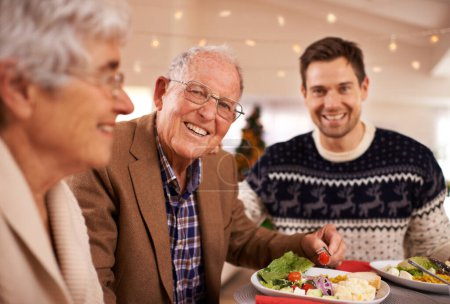 Téléchargez les photos : Grand-père, portrait et famille au dîner de Noël avec nourriture et célébration à la maison. Heureux, événement et vieil homme sourire avec assiette au déjeuner et se détendre pendant les vacances à table avec les gens. - en image libre de droit