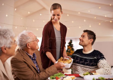 Foto de Familia, cena y sonrisa en la mesa en Navidad, junto con comida y celebración en casa. Senior, madre y padre con felicidad en el almuerzo con la mujer anfitriona de vacaciones y plato de pollo en el plato. - Imagen libre de derechos