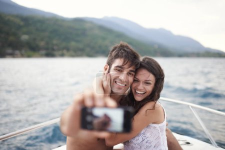 Téléchargez les photos : Couple, vacances et selfie en bateau, océan et Bali pour une escapade avec sourire et affection. Homme, femme et amour pour le téléphone, heureux et Voyage sur yacht et vacances d'été par la montagne et l'eau. - en image libre de droit