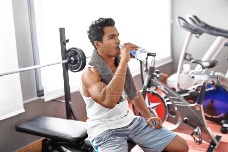 Photo for Gym, fitness and man drinking water for training, wellness or exercise recovery, break or resting. Workout, hydration and thirsty male athlete with sports drink after intense, cardio or bodybuilding. - Royalty Free Image