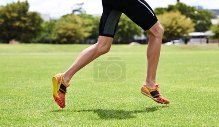 Téléchargez les photos : Athlète, courir et en plein air pour la course, les jambes et les vêtements de sport dans l'entraînement et l'entraînement pour le bien-être et le jogging cultivé. Cardio, bien-être et sport pour l'exercice, la santé et la forme physique sur herbe pour chaussures d'été. - en image libre de droit