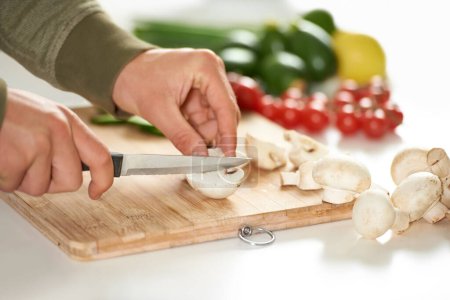 Photo for Diet, cooking and hands cutting mushroom on kitchen counter with salad, wellness and nutrition in home. Board, knife and healthy food with vegetables at brunch, chef and vegan meal prep in apartment. - Royalty Free Image