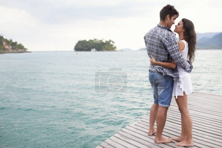 Photo for Date, holiday and couple hug by lake in vacation, water and outdoor for nature in summer for romance. Partners, woman and man together to travel, journey and adventure in ocean for love with embrace. - Royalty Free Image