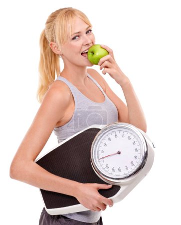 Photo for Portrait, scale and woman with apple for progress, diet benefits or food to lose weight in studio. Healthy eating, nutrition and happy girl with fruit for weightloss, digestion and white background. - Royalty Free Image
