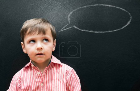 Photo for Child, boy and thinking with speech bubble on blackboard for creative idea, drawing and illustration in classroom. Student, kid and face with daydreaming, contemplating and question with chalkboard. - Royalty Free Image
