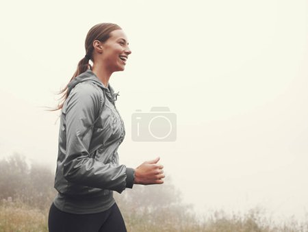 Téléchargez les photos : Nature, énergie et femme courant dans le brouillard sur route de montagne pour la course, le marathon ou l'entraînement de compétition. Sport, exercice et athlète avec entraînement cardio pour la remise en forme dans les bois de plein air brumeux ou la forêt - en image libre de droit