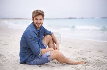 Photo for Portrait, beach and man with a smile, travel and summer holiday with weekend break and water. Waves, face and person with happiness and guy with seaside and journey with vacation or sand with freedom. - Royalty Free Image