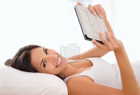 Photo for Woman, tablet and reading in bed, portrait or story with ebook, knowledge or subscription in house. Girl, person and smile with digital touchscreen for streaming app to relax at apartment in morning. - Royalty Free Image