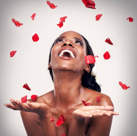Téléchargez les photos : Fleur, lancer et femme noire en studio pour maquillage, beauté ou bien-être sur fond gris. Confettis floraux, sourire et modèle africain avec des cosmétiques doux, brillants ou bio, fun et transformation. - en image libre de droit