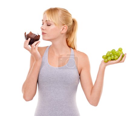 Photo for Woman, temptation and dessert over fruit in studio with white background in backdrop. Girl, choice and decision between muffin or grapes for nutrition in food, think and care for wellness of body. - Royalty Free Image