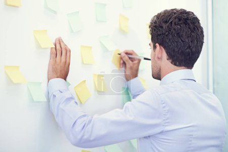 Photo for Businessman, writing and sticky notes in office for planning, brainstorming and project strategy with rear view. Entrepreneur, employee and ideas for agenda, schedule and proposal information at work. - Royalty Free Image