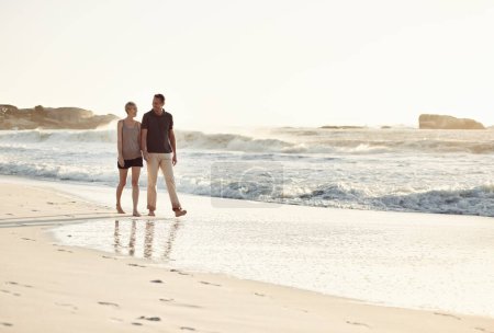 Photo for Couple, talking and beach at sunset for romantic date, weekend getaway or vacation in Indonesia. Happy woman, man or people in love with smile for evening walk, bonding and relaxation by shore. - Royalty Free Image