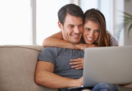 Laptop, smile and woman embracing man on sofa networking on social media, website or internet. Happy, love and female person hugging husband reading online blog with computer in living room at home
