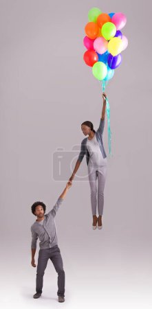 Photo for Balloon, float and couple in studio for birthday, celebration and present on gray background. Trust, flying and isolated man and woman holding hands with inflatable for party, gift and surprise. - Royalty Free Image