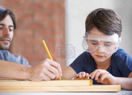 Photo for Father, kid and woodwork at home for project, bonding and building with safety gear. Dad, son and carpenter for renovating, measuring and teaching with help for development of house with goggles. - Royalty Free Image