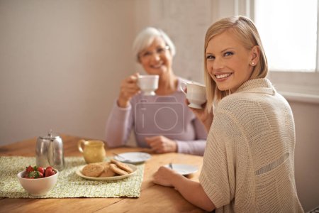 Photo for Portrait, happy woman and senior mother drinking coffee at breakfast, bonding and smile in house. Face, elderly mom and adult with tea cup at table, food and family eating cookies at home together. - Royalty Free Image