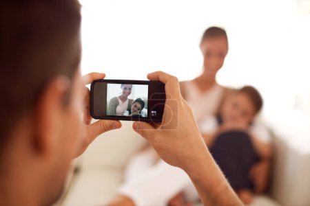 Père prenant une photo de famille, la maison et l'écran avec smartphone et les médias sociaux dans un salon. Parents, mère et père avec fille ou enfant avec mémoire et utilisateur mobile avec application numérique ou réseau.