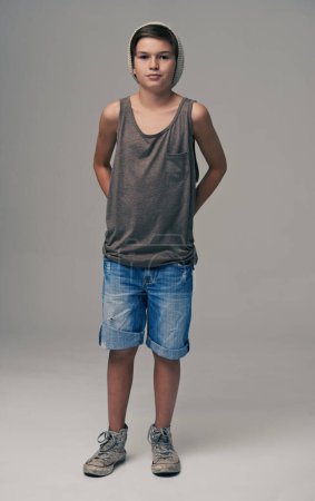 Photo for Young boy, portrait and fashion with denim shorts or jeans for style on a gray studio background. Male person, child or teenager with summer clothing or cool stylish outfit with beanie on mockup. - Royalty Free Image
