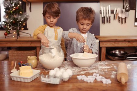 Photo for Kids, baking and playing in home with flour, love and bonding with ingredients for dessert cake. Boys, mixing or bowl for christmas cookies on counter, eggs or learning of pastry recipe by cutter. - Royalty Free Image