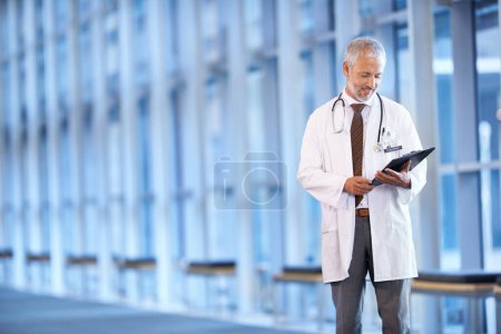 Photo for Checklist, happy doctor and man reading in hospital for healthcare, wellness and notes. Clipboard, medical professional and smile of mature surgeon with paper, results and report on chart in clinic. - Royalty Free Image