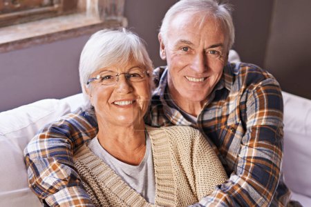 Photo for Senior couple, hug and portrait on sofa with smile, love and connection in living room for retirement. Elderly woman, old man and embrace on couch in lounge with pride, care and happy in apartment. - Royalty Free Image