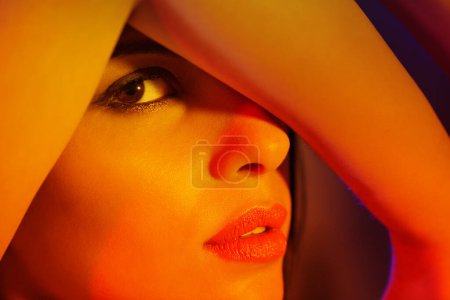 Photo for Studio, woman or portrait in artistic lighting with eye peeping, creativity or cover with arm to hide. Model, cosmetic and creative face for art deco, aesthetic and skincare for dermatology or beauty. - Royalty Free Image