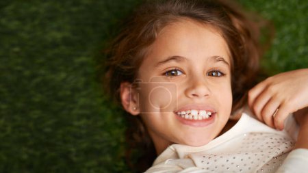 Photo for Portrait, girl or happy to relax in childhood, fun or play on grass in garden, park or backyard. Smile, child or lying in free time, leisure or break in carefree, outdoor activities on mockup space. - Royalty Free Image