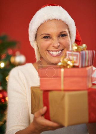 Photo for Christmas, present and woman in portrait for holiday, celebration and tradition on a red or wall background. Excited, happy and young person by tree with bokeh lights, gift or giving box at home. - Royalty Free Image