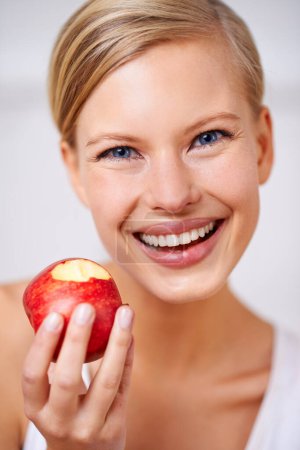 Photo for Happy woman, portrait and nutrition with red apple in fitness, health and wellness on a gray studio background. Face of female person with smile and natural organic fruit for vitamins, fiber or snack. - Royalty Free Image